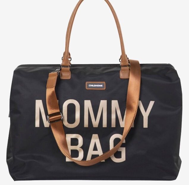 Die Mommy Bag ist eine weiße oder schwarze Wickeltasche mit einem länglichen, rechteckigen Körper. Sie besitzt einen Tragegriff oben sowie zwei seitliche Taschen und ein großes Fach auf der Vorderseite. Der Schriftzug 'Mommy Bag' ist mittig auf dem Vorderfach angebracht.