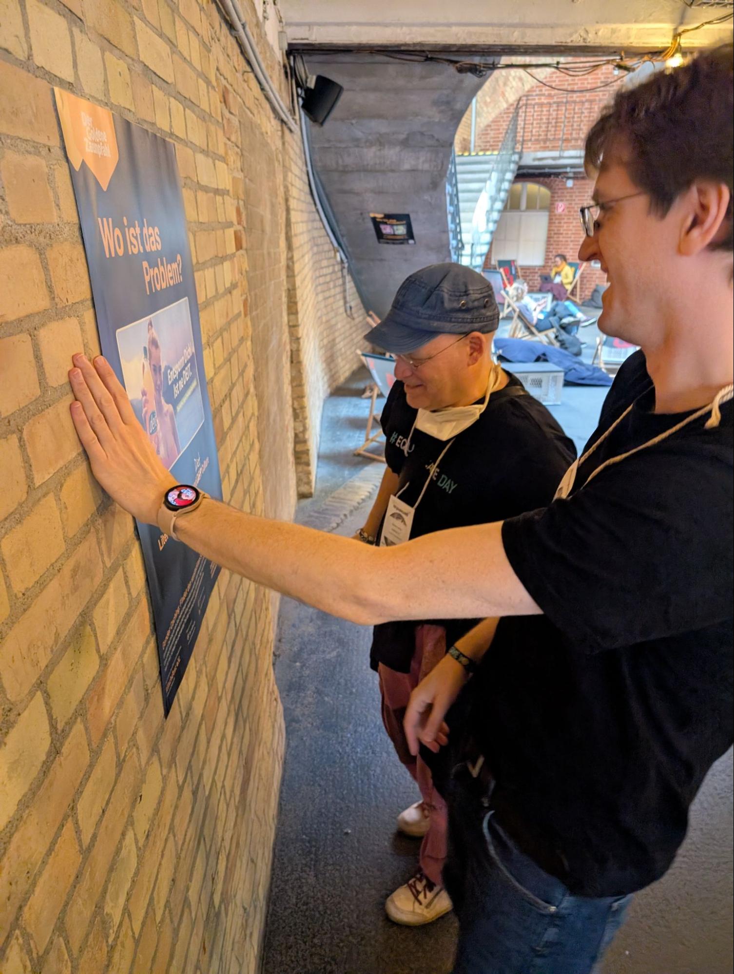 Sascha und Clemens hängen eines der Gender Caching Plakate auf dem Veranstaltungsgelände der re:publica auf